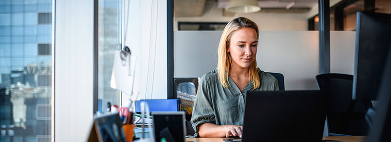 mujer sentada en la oficina trabajando con su computadora