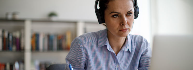Mujer concentrada con auriculares trabajando en la computadora
