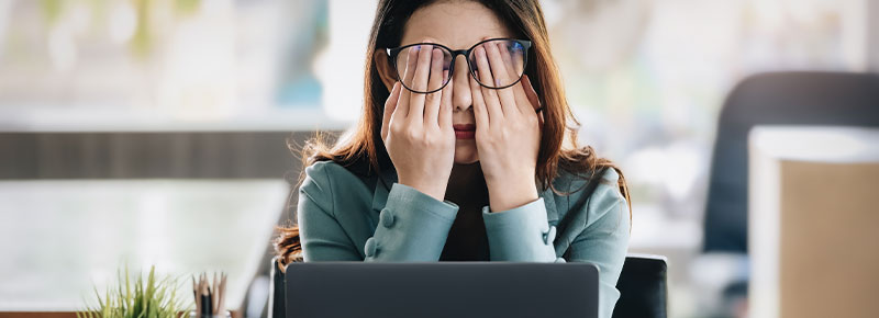 mujer en oficina con signos de estres laboral