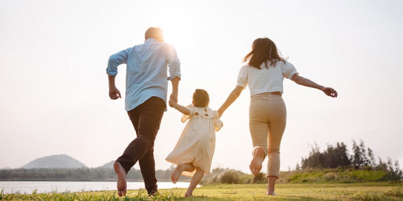 Familia descalza corriendo de la mano por el cesped