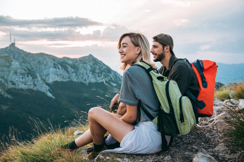 pareja joven tomando un descanso luego de hacer senderismo